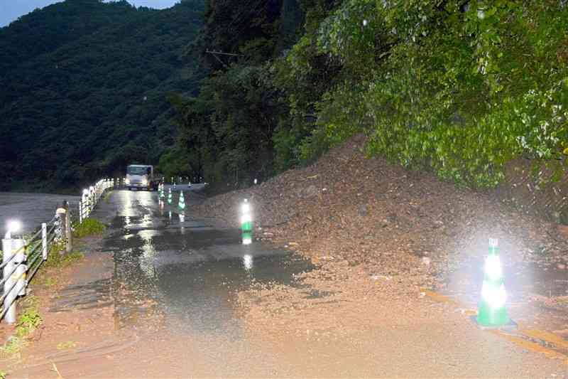 土砂崩れで車線の片側がふさがれた国道219号。左は球磨川＝15日午後7時10分ごろ、球磨村渡