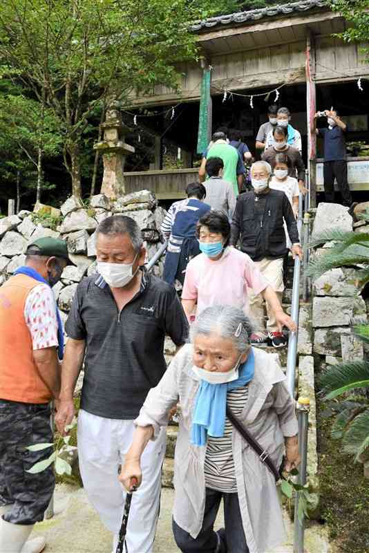 カシの葉を手に早浦阿蘇神社にお百度参りする住民たち＝天草市