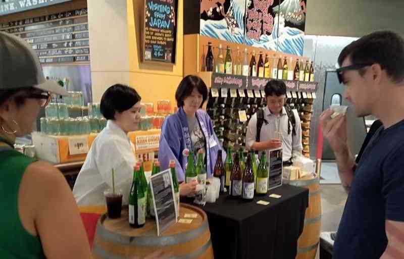 5月に米国のスーパーで開かれた日本酒の販売促進イベント。試飲を勧め商品を説明する千代の園酒造の本田裕理取締役（左から2人目）（同社提供）
