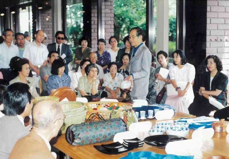 「くらしの工芸展」（県伝統工芸館、熊日共催）の講評で、入賞作品を手に講話する審査員の秋岡芳夫氏＝1991年9月（県伝統工芸館提供）