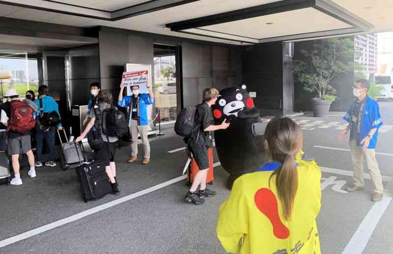 宿泊先のホテルで、くまモンと県職員らの出迎えを受ける米国の高校生ら＝22日、熊本市中央区