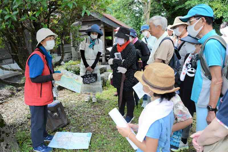 阿蘇神社近くの湧水群でガイド（左）の説明を聞く参加者ら＝阿蘇市