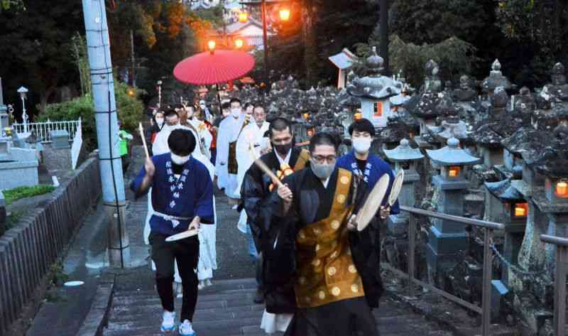 うちわ太鼓を打ち鳴らしながら階段を上る本妙寺の「頓写会」の行列＝23日夜、熊本市西区