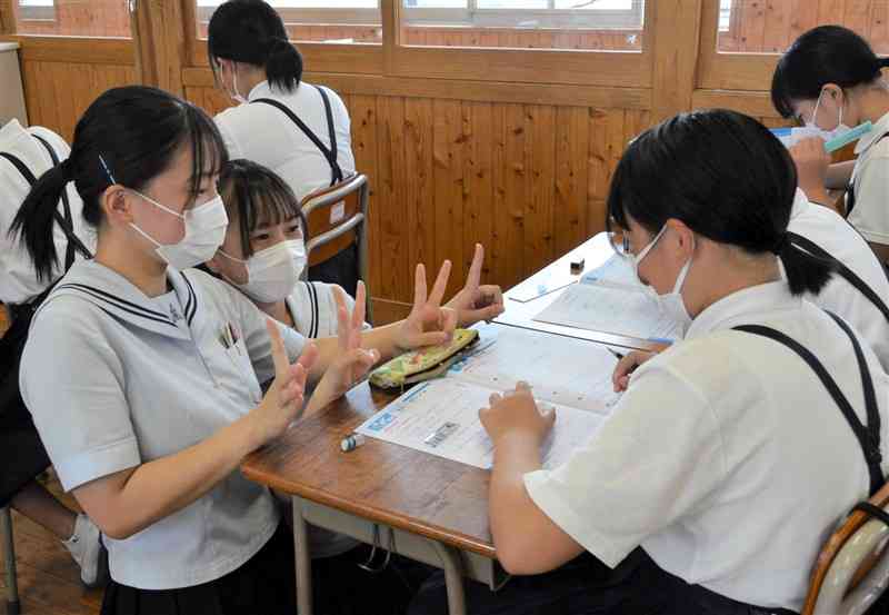 小学生（右）に分かりやすく算数を教える菊池高の生徒ら＝菊池市