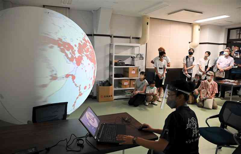 大型の球状スクリーンを使った地球儀で、過去の地震について学ぶ参加者＝30日午前、南阿蘇村