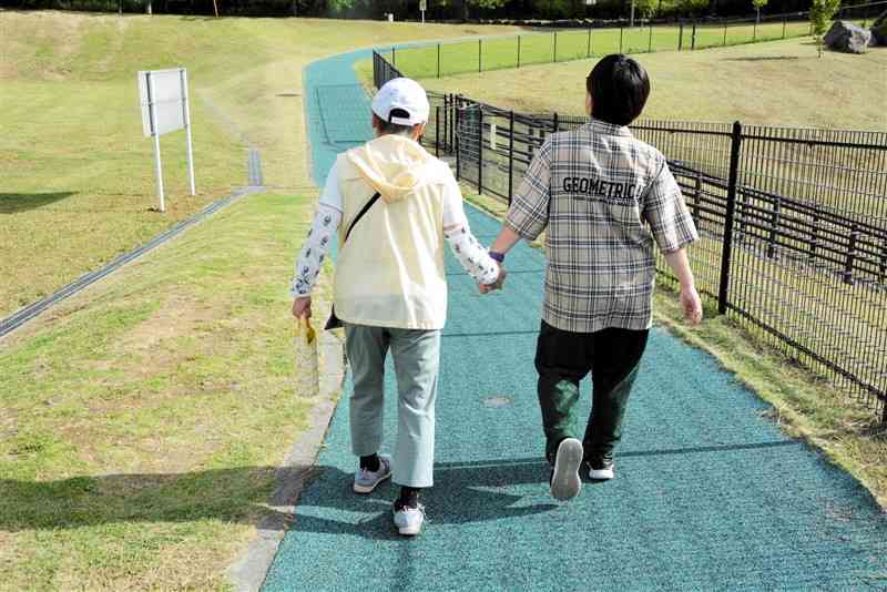 知的障害のある母親と歩く塚本陽子さん（右）。幼い頃から外出時は常に手をつないで歩いた＝熊本市