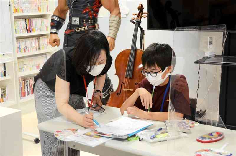 「中央区まちづくりマンガスクール」で子どもにアドバイスをするさいきゆみさん（左）＝熊本市中央区