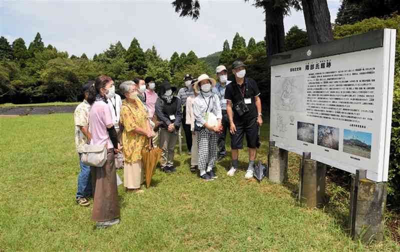 隈部氏館跡を訪れ、案内看板を囲む肥後国衆一揆の史跡巡りツアーの参加者＝山鹿市