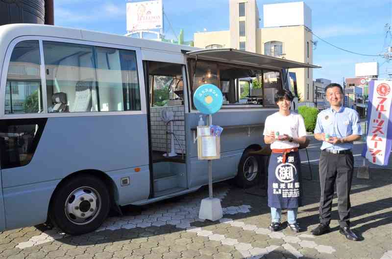 JR玉名駅前にキッチンカーを出店した大渕峰昇さん（左）とJR九州の鹿島敬宏・新玉名駅長＝玉名市