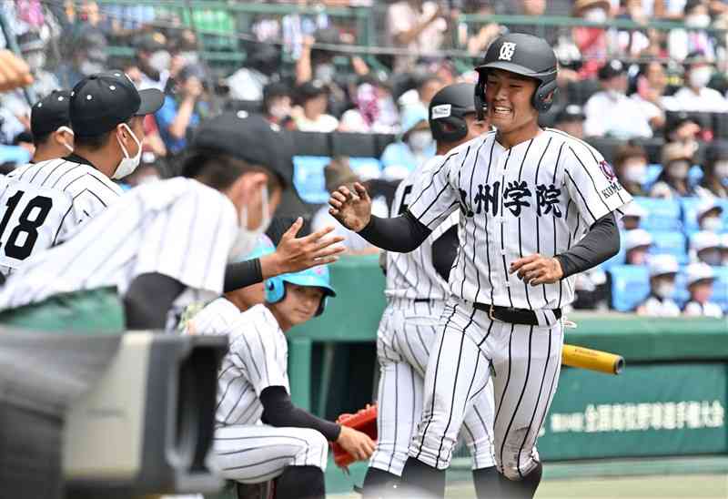 【九州学院－帝京五】1回裏、九州学院無死一、三塁。園村の右前打で三走大城戸が生還。1－1の同点に追い付きベンチ前でハイタッチ＝甲子園（谷川剛）