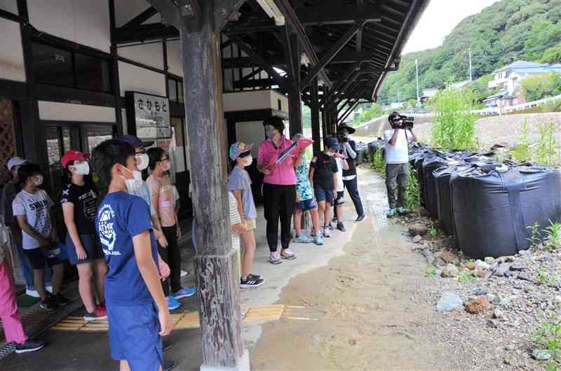 熊本豪雨で大きな被害を受けたJR肥薩線坂本駅を訪れ、説明を聞く小学生ら＝八代市