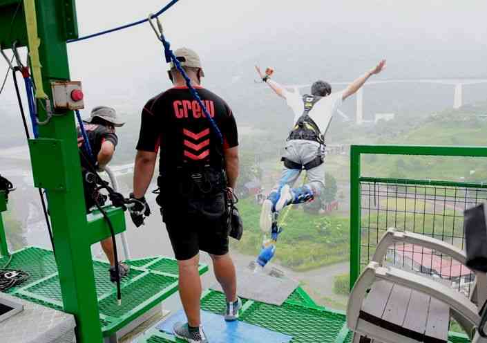 眼下の川辺川に向かってバンジージャンプをする観光客。手前2人はスタッフ＝五木村