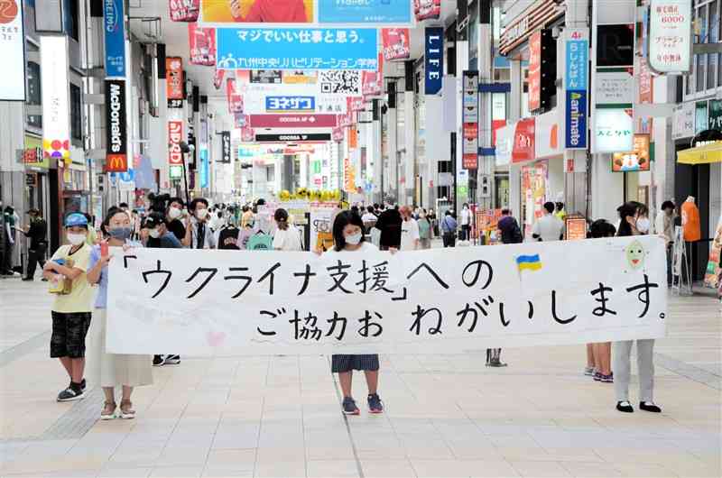 手作りの横断幕を掲げて、募金を呼びかける武蔵小の児童ら＝熊本市中央区