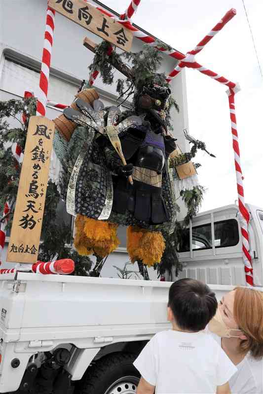 造り物で特賞を獲得した「風を鎮める烏天狗」を見上げる家族連れ＝20日、高森町