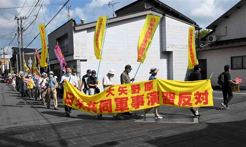 横断幕やプラカードを掲げて日米共同訓練への反対を訴えるデモ行進の参加者＝山都町