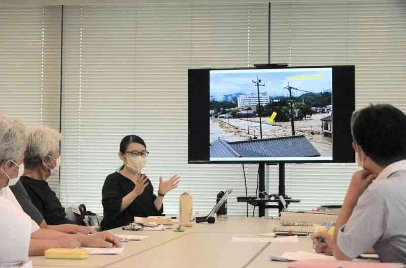 豪雨災害時の人吉大橋付近の写真を示し、「危機管理型水位計は水没していた」と主張する市民団体のメンバーら（左側）＝23日、県庁