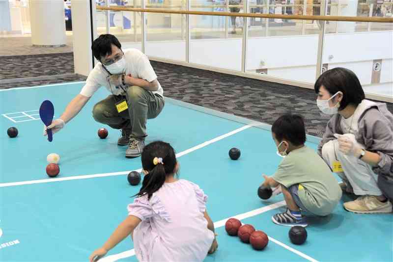 ボッチャの体験会で、子どもたちに競技方法を教える吉田祐一さん（奥）＝嘉島町