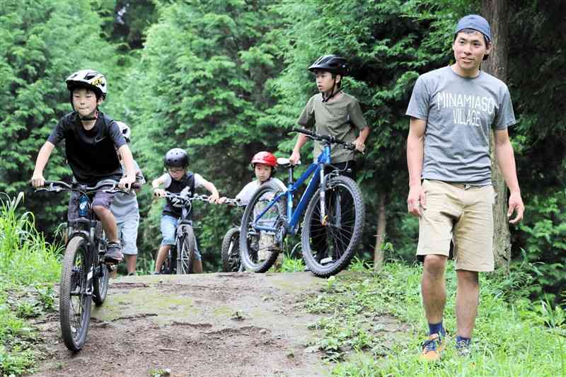 完成間近のマウンテンバイクコースで乗り方を指導する山内健正さん（右）＝南阿蘇村