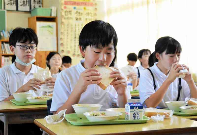 国産小麦粉100%の食パンを頰張る嘉島東小の児童＝12日、嘉島町