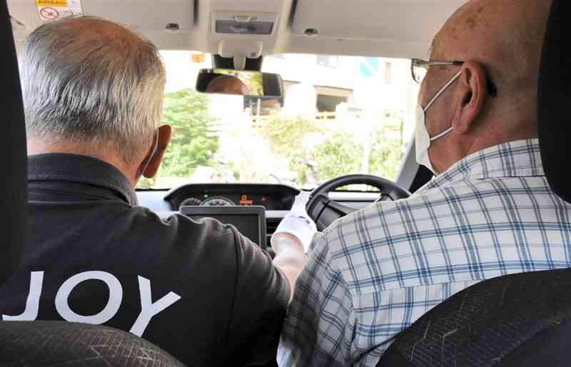 寺原自動車学校で高齢者講習を受ける男性（右）。指導員から安全運転のアドバイスを受けていた＝熊本市中央区