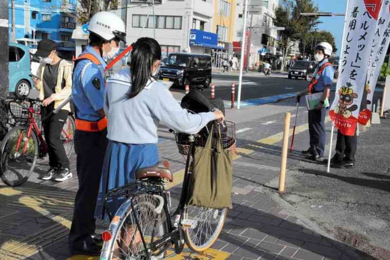 自転車で通学中の高校生に安全指導をする警察官＝20日午前7時55分ごろ、熊本市中央区