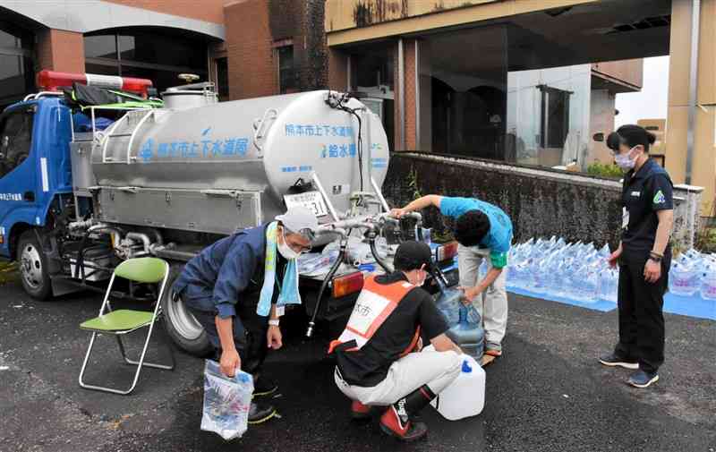 旧岡原村役場で給水活動に取り組むあさぎり町と熊本市上下水道局の職員＝22日午前10時半ごろ、あさぎり町