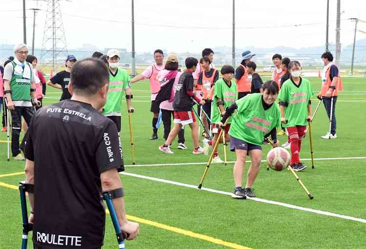 松葉づえを使う「アンプティサッカー」に挑戦する参加者ら＝嘉島町の県フットボールセンター
