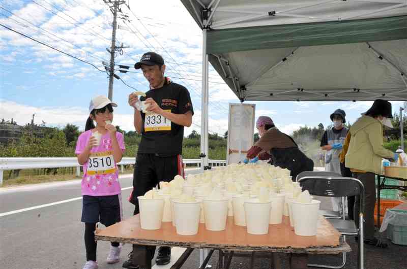 氷川町梨マラソンの試食ブースでナシを手にする参加者＝氷川町
