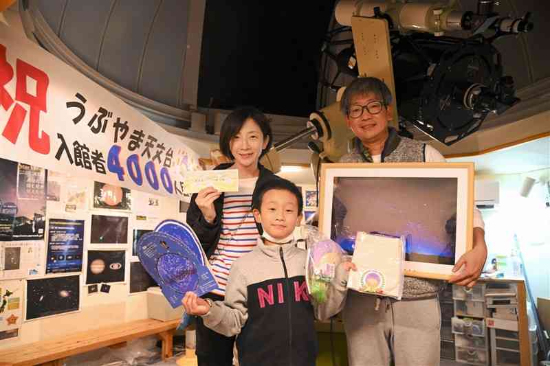 うぶやま天文台の4000人目の来場者となった松田樹輝君（中央）と両親＝産山村