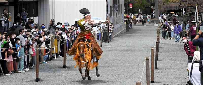 流鏑馬で疾走する馬にまたがり弓矢を放つ射手＝阿蘇市