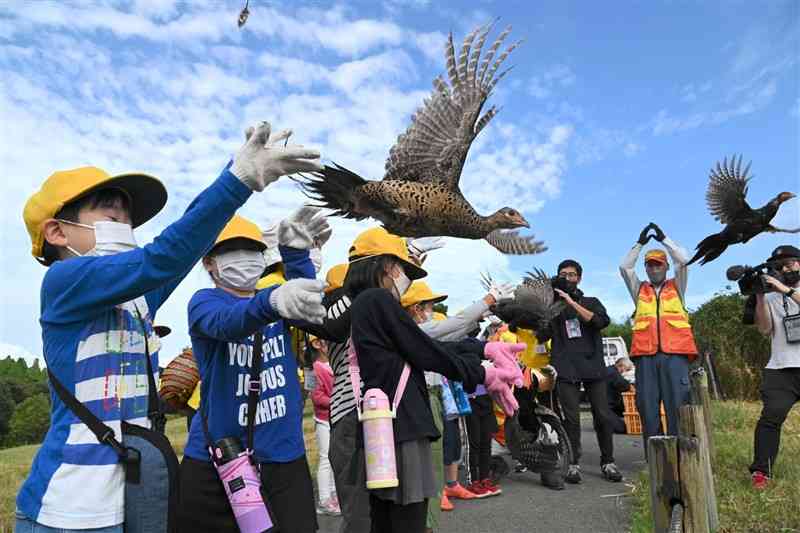 阿蘇中部猟友会員の指導でキジを放つ阿蘇小の1年生＝阿蘇市