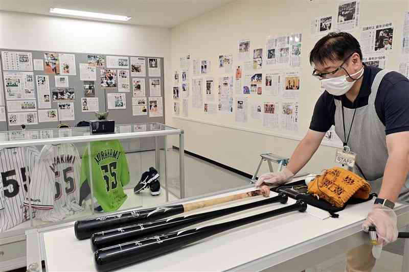 特別展「村上宗隆選手の歩み」に展示されるサイン入りバットやユニホーム＝6日午後、熊本市中央区の新聞博物館（谷川剛）