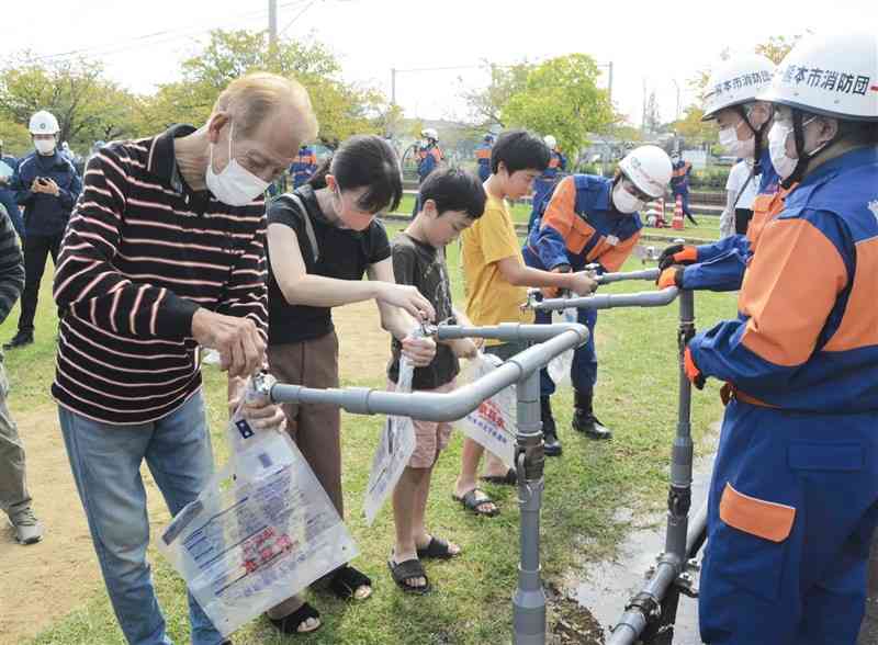 防災実動訓練で、給水袋に飲用水を入れる住民ら＝熊本市西区