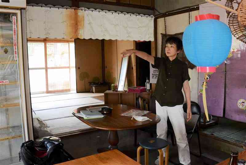 住民の交流の場だった旧丸山商店の店内に立つ丸山るみ子さん。当時のまま今もテーブルが置かれている＝菊池市