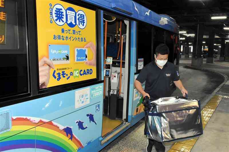 美里町から運んだ荷物を路線バスから降ろす九州産交バス職員＝22日、熊本市中央区