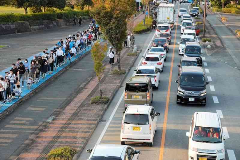 サッカーの試合後、車が数珠つなぎとなった「えがお健康スタジアム」周辺の道路。バスを待つ長蛇の列もできていた＝23日午後4時半ごろ、熊本市東区