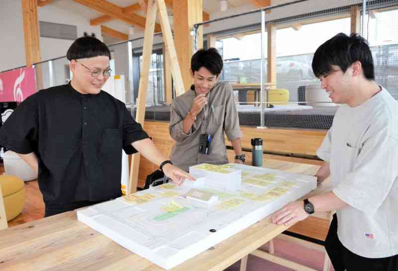 施設整備が進む「にじいろ」一帯の模型を囲む（左から）吉海雄大さん、中村康佑さん、小仲貴宏さん＝益城町
