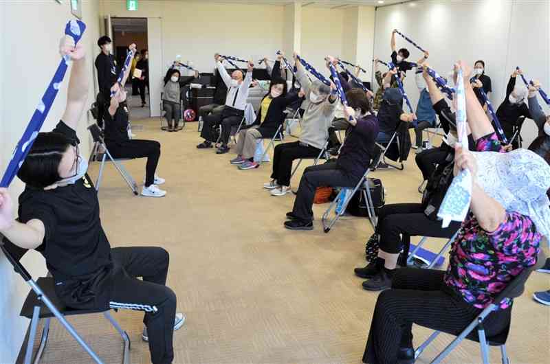 九州看護福祉大の学生（左）から健康維持に役立つ体操を習う参加者＝玉名市