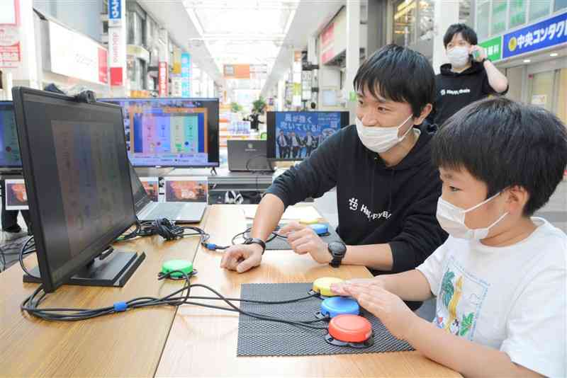 eスポーツのイベント会場で、障害者とオンラインでゲームを楽しむ子ども（手前）＝熊本市中央区