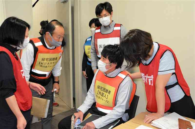 訓練で、体調不良を訴える帰宅困難者から要望を聞く医師ら＝熊本市西区