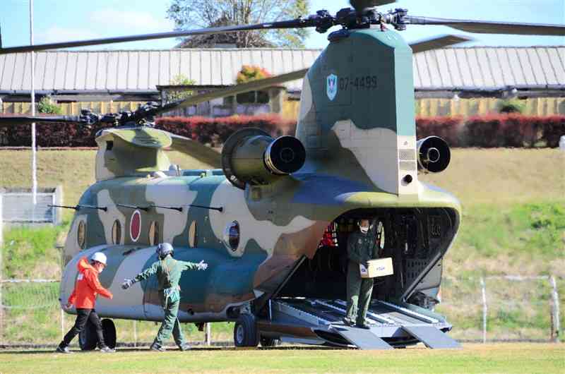 通信設備が損傷した高森町へ届ける復旧物資を大型ヘリコプターから運び出す航空自衛隊の隊員ら＝3日、南阿蘇村