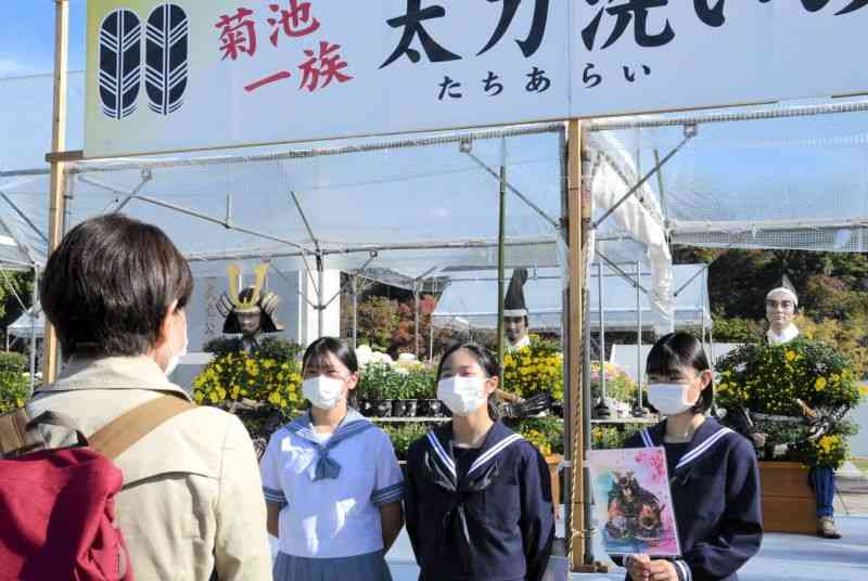 「菊人形・菊まつり」の会場で菊池一族の歴史などをガイドする菊池南中の生徒たち＝菊池市