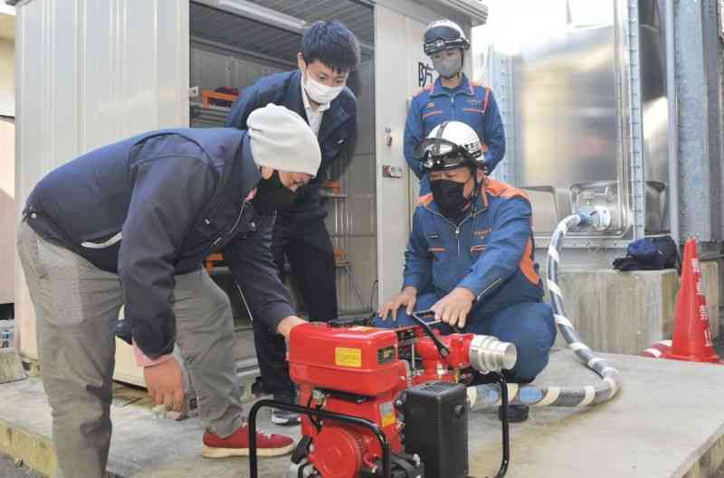 可搬ポンプの使い方を消防隊員（手前右）から教わる訓練参加者ら＝8日、熊本市西区