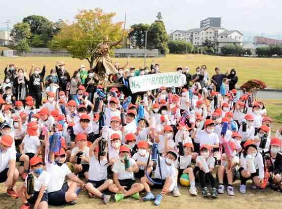 ゾロの銅像の前で誕生日を祝って乾杯する参加者＝11日、大津町