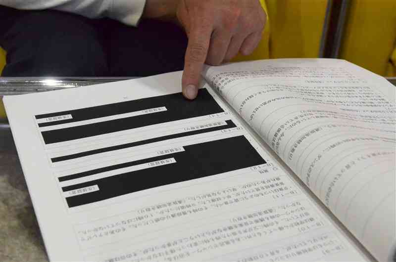 県の第三者機関がまとめた調査報告書の黒塗り部分を示す遺族＝10月中旬、熊本市中央区
