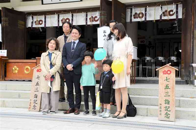 加藤神社の社殿を背景に記念写真に納まる参拝客ら＝熊本市中央区