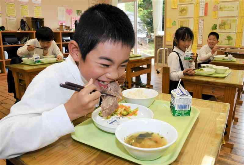 給食のポークステーキをうれしそうに食べる天草小の2年生＝天草市