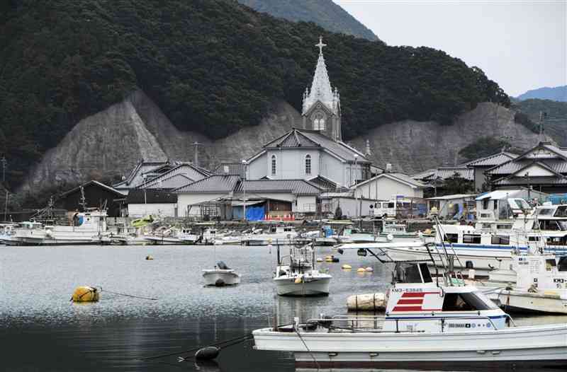 海から見た﨑津集落と﨑津教会。防災のための治山整備では、斜面のモルタルを落ち着いた色合いに着色した＝天草市