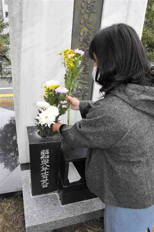 大洋デパート火災犠牲者の慰霊碑に花を手向ける遺族の原田真羊さん＝17日、熊本市中央区