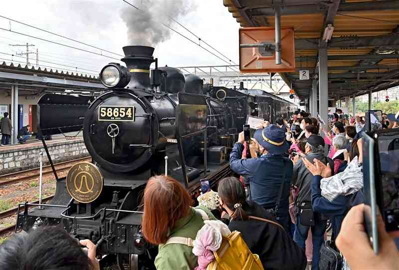 SL人吉の蒸気機関車「58654号機」の誕生100年記念イベントで、JR八代駅に入構する列車を出迎える鉄道ファンら＝18日午前、八代市（石本智）